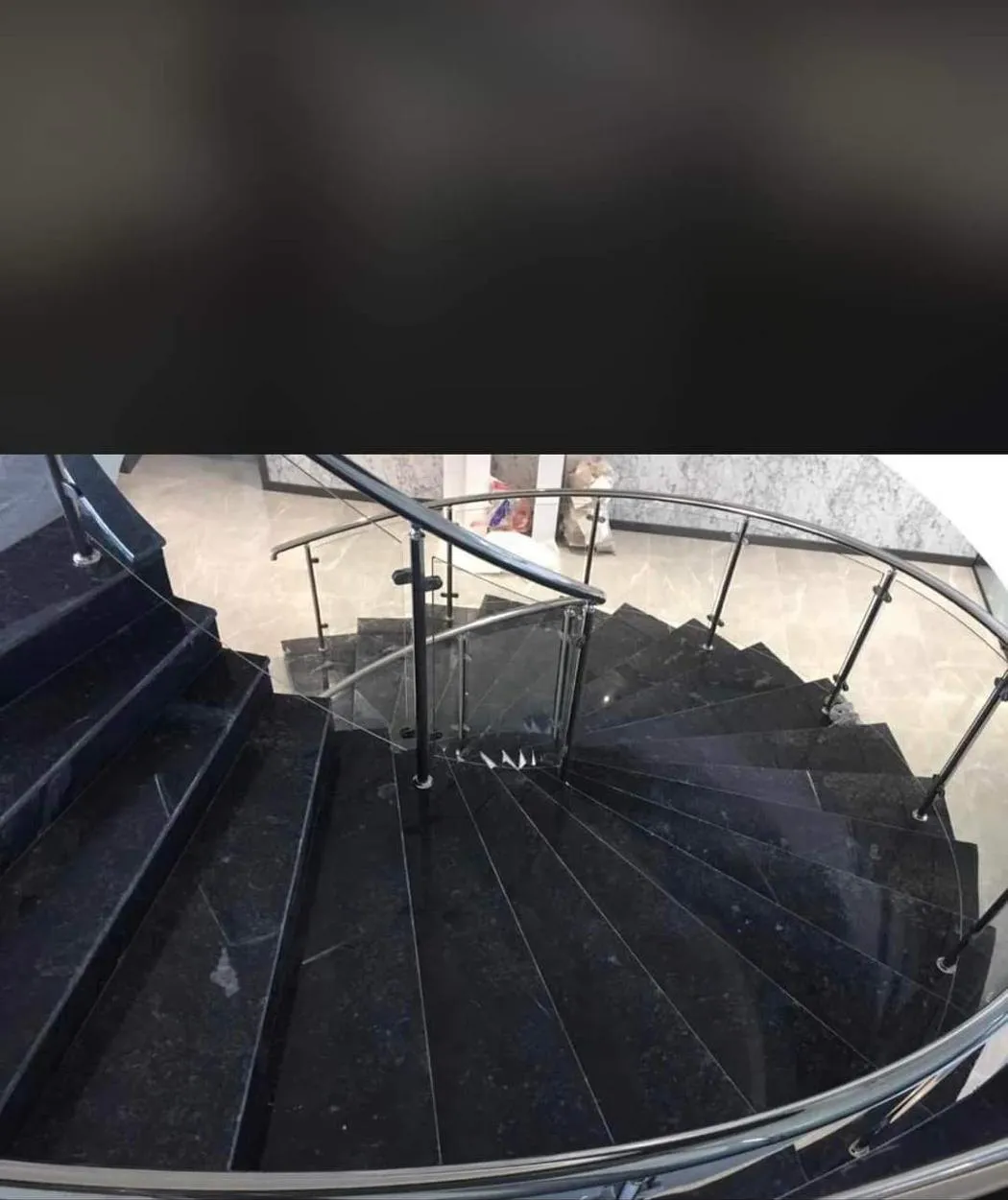 Spiral staircase in black marble with a glass and steel balustrade