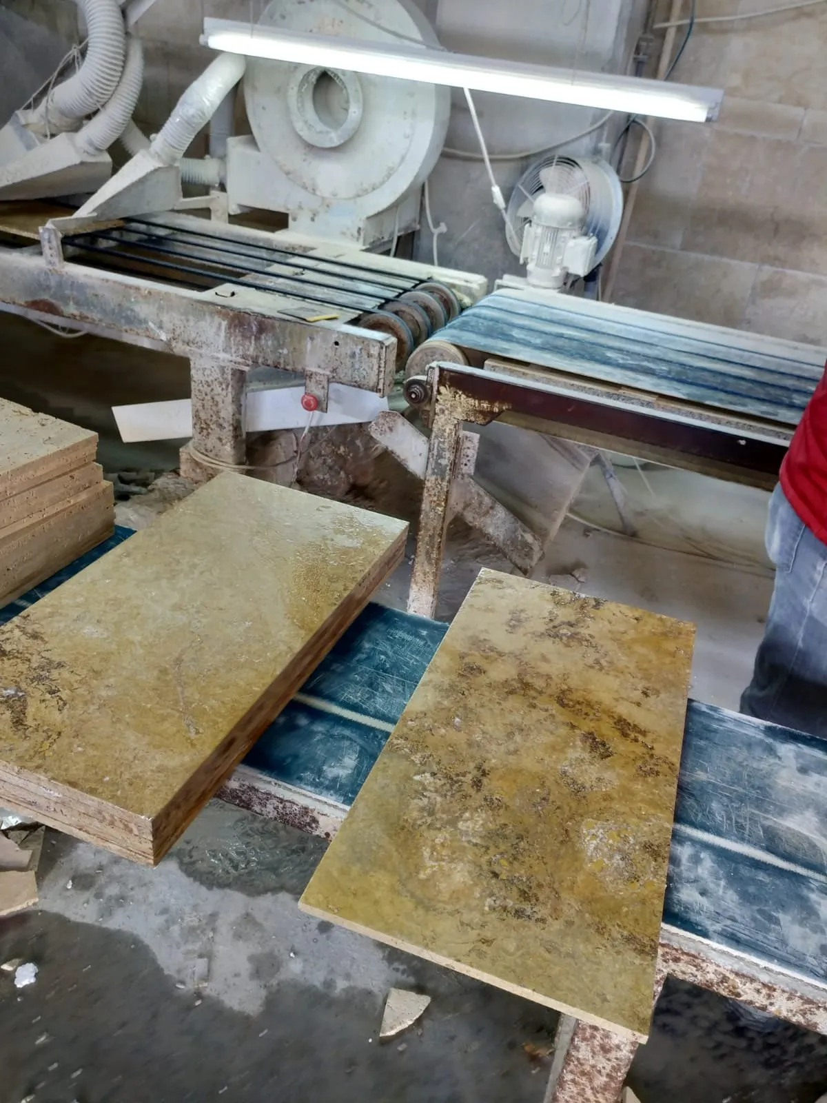 Travertine tiles on a cutting and calibration machine in the workshop